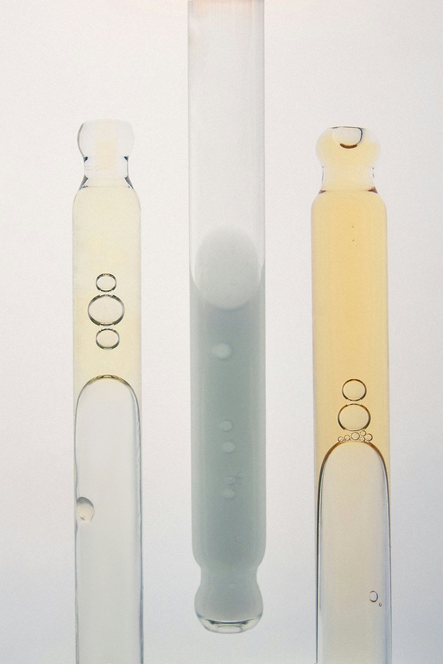Three glass droppers holding pale serums